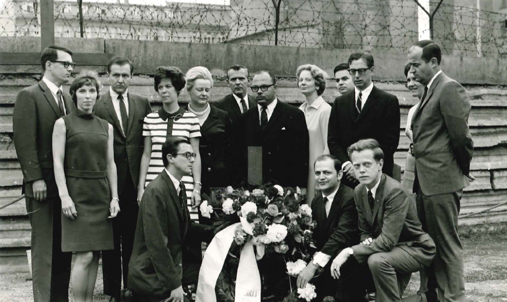 Group of delegates posing with flowers in the middle.
