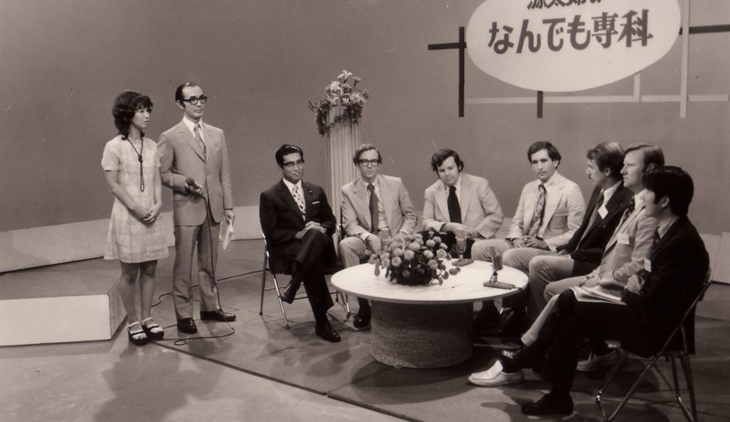 American delegates seated around a table for a TV interview in Japan