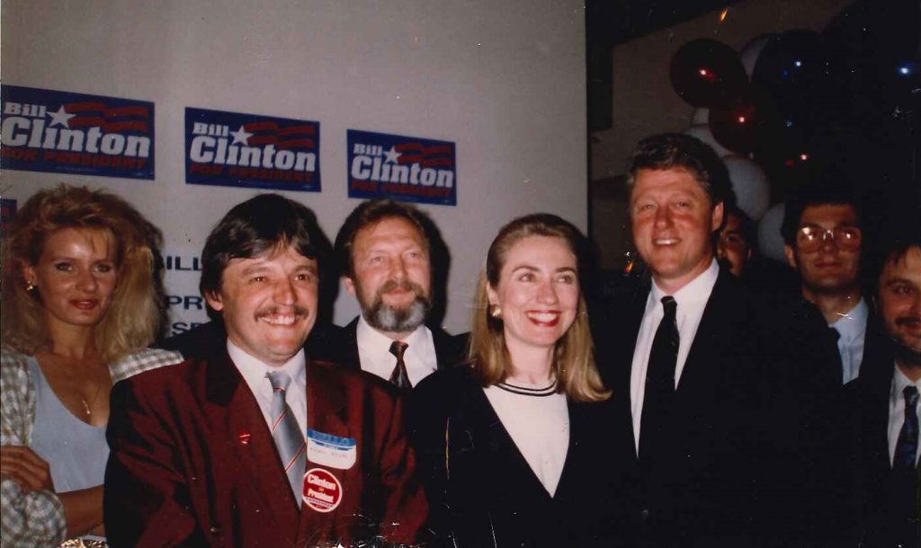 Bill and Hillary Clinton posing with delegates from Hungary with Clinton campaign signage behind them.