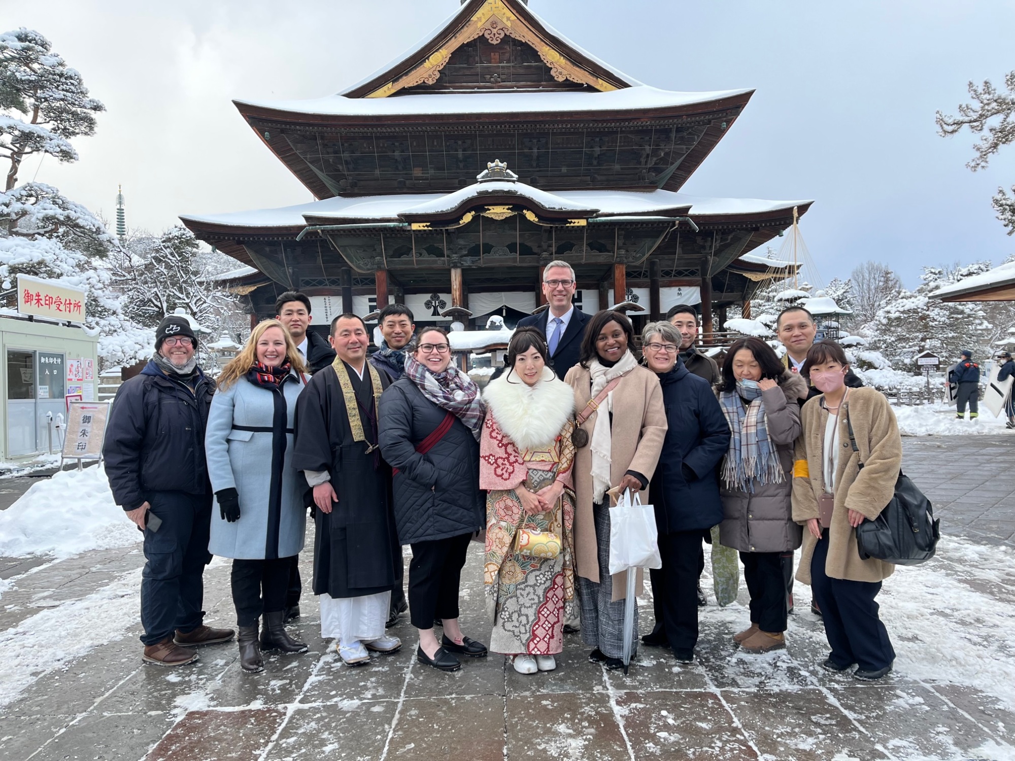 ACYPL delegates standing with Japanese leaders in front of a temple on a snowy, wintery day.