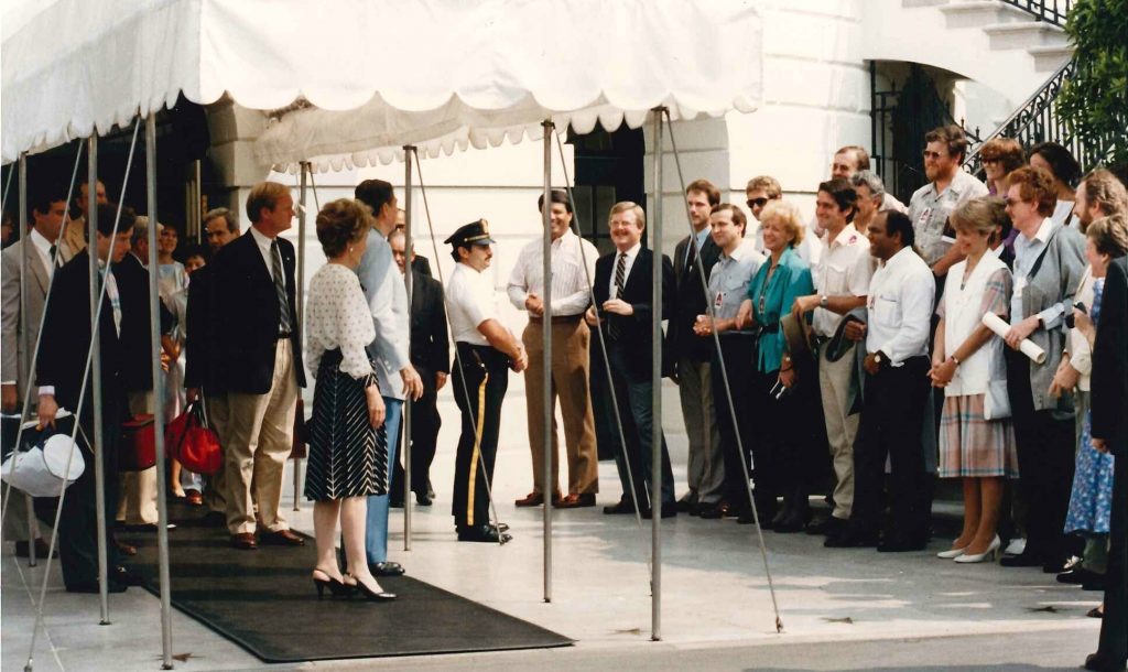 Pres. and Nancy Reagan standing under a canopy at an entrance of the White House greeting Australian delegates standing a few feet away.